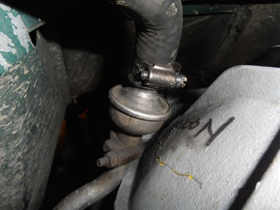 Metal check valve with black hose and screw clamp in an engine bay
