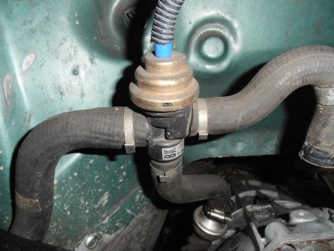 1990 Ford Bronco - A close-up view of an engine component, likely part of the emissions system, with hoses connected.
