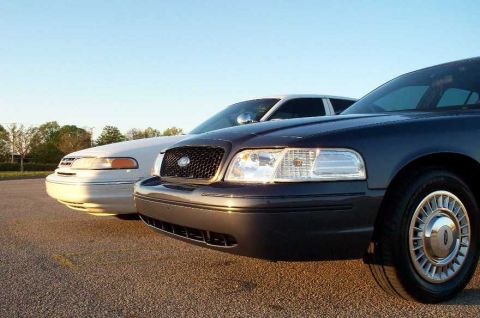 1998 Ford Crown Victoria - Two Ford Crown Victorias parked side-by-side under a clear sky.