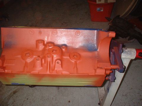 1957 Ford Custom Sedan - An engine block, painted orange with blue and purple accents, sits on a stand.
