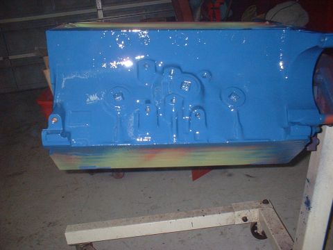 1957 Ford Custom Sedan - A freshly painted blue engine block sits on a stand in a garage, showing signs of previous colorful primer.