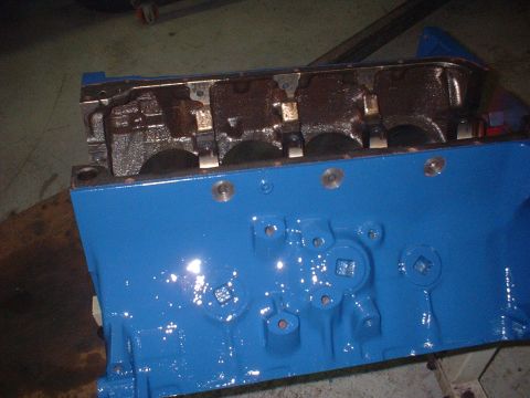 1957 Ford Custom Sedan - A blue painted engine block is shown, with internal components visible at the top and bolt holes on the side.