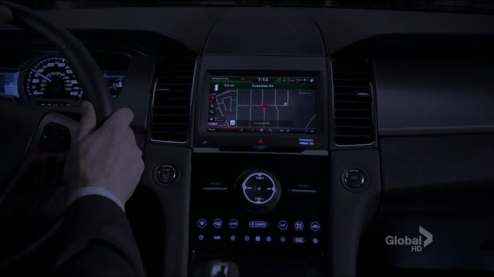 Car interior dashboard at night, showing a navigation screen with a map, steering wheel, and instrument cluster