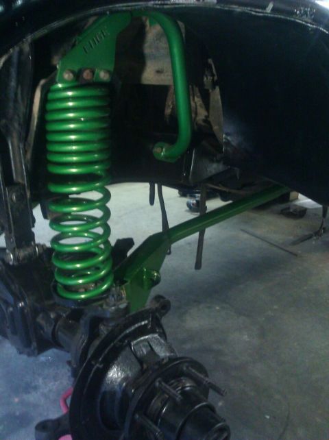 1979 Ford Bronco - Close-up view of a vehicle's suspension system, highlighting a bright green coil spring and sway bar assembly.