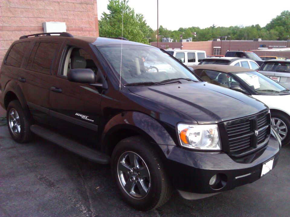 Black SUV with chrome wheels, side step, and 'Night Runner' badge parked outdoors