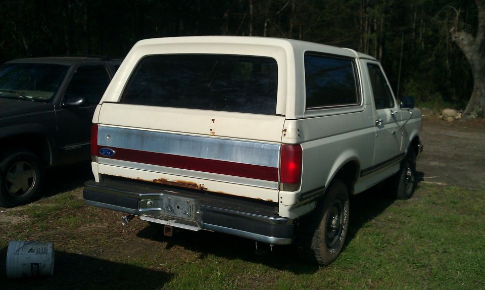 White 1987 Ford Bronco rear view, showing rust on the bumper and tailgate