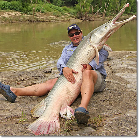 1993 Ford Bronco - A man proudly displays a massive alligator gar he caught near a river.