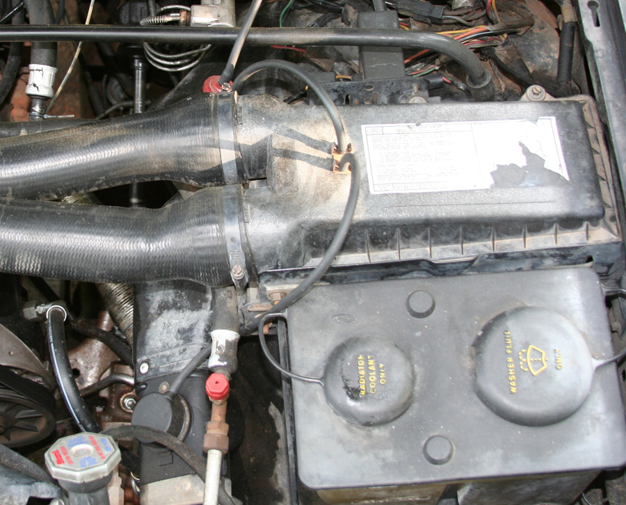 Engine bay with air box, intake tube, and dual coolant/washer fluid reservoir with yellow labels