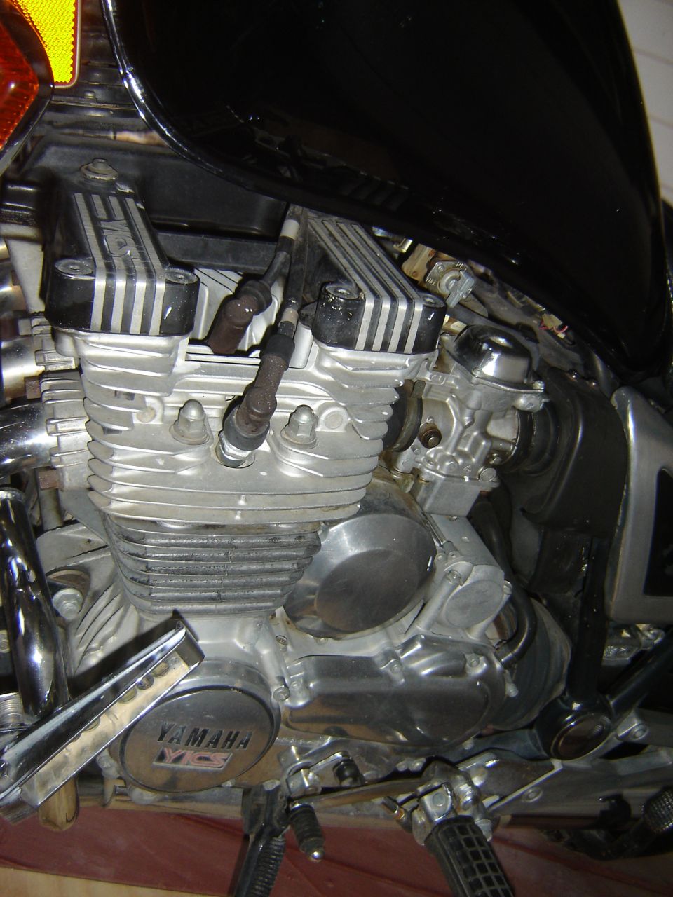 Motorcycle engine with Yamaha XJ7Maxim badge, showing cylinders, carburetor, and spark plugs