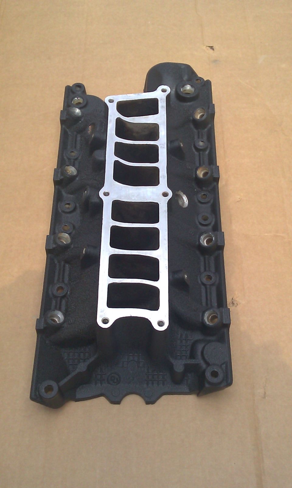 Black lower intake manifold for a V8 engine on a white surface
