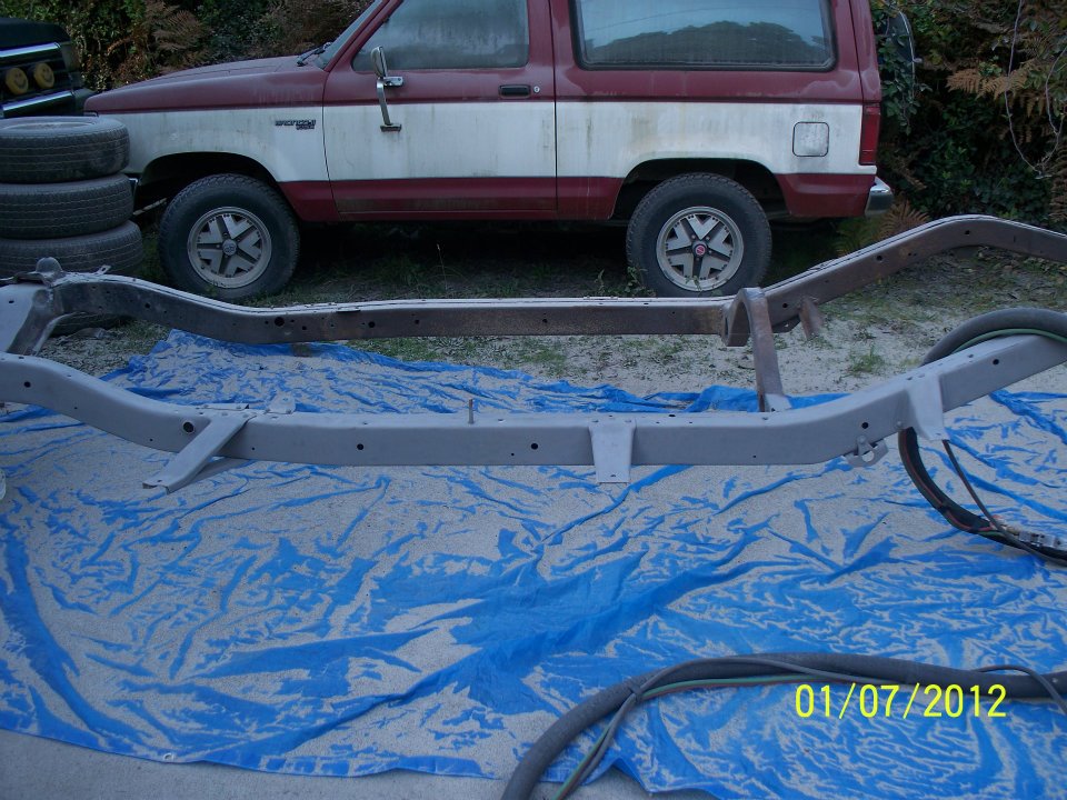 1990 Ford Bronco parked behind its chassis on a blue tarp