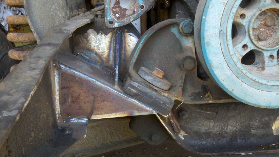Close-up of engine bracket and pulley assembly, showing welds and wear