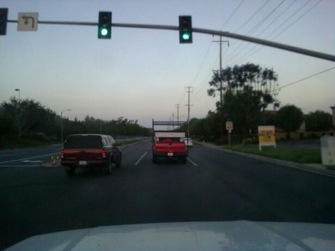 1988 Ford Bronco - Two vehicles drive down a road as the traffic light turns green.