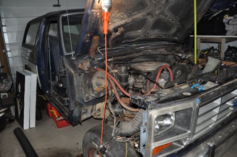 1986 Ford Bronco - The engine bay of a 1986 Ford Bronco is visible with the hood open, revealing the engine and front grille.