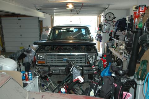 1986 Ford Bronco - The front of a Ford Bronco is visible in a garage, surrounded by various items and sporting equipment.