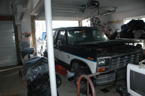 1986 Ford Bronco - A dark blue and white Ford Bronco is parked in a garage with its hood open, and another vehicle is visible in the background.