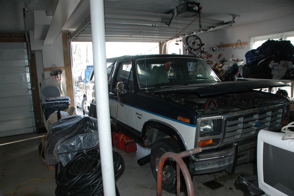Dark blue and white Ford Bronco with hood open, parked in a garage