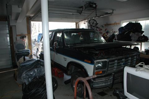 1986 Ford Bronco - A two-tone 1986 Ford Bronco is parked inside a garage with its hood open.