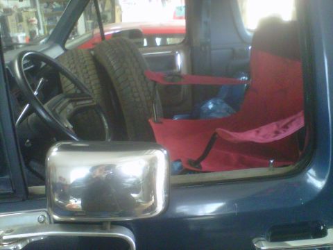 1986 Ford Bronco - Spare tires and red seats are visible inside the vehicle's cabin, with another vehicle in the background.