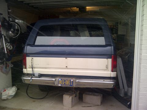 1986 Ford Bronco - Rear view of a two-tone white and blue SUV, possibly a Ford Bronco, parked inside a garage.