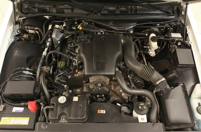 Engine bay with V8 engine, air intake, battery, and various hoses and wires
