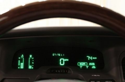 2004 Mercury Grand Marquis - The digital dashboard displays speed, mileage, fuel level, and engine temperature, with a wooden steering wheel in view.