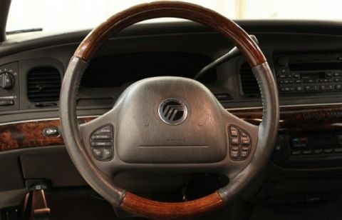 2004 Mercury Grand Marquis - Interior view of a car's steering wheel and dashboard, showing wood trim and control buttons.
