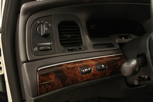 Dashboard of a 2004 Mercury Grand Marquis showing headlight controls, air vents, and wood trim around buttons