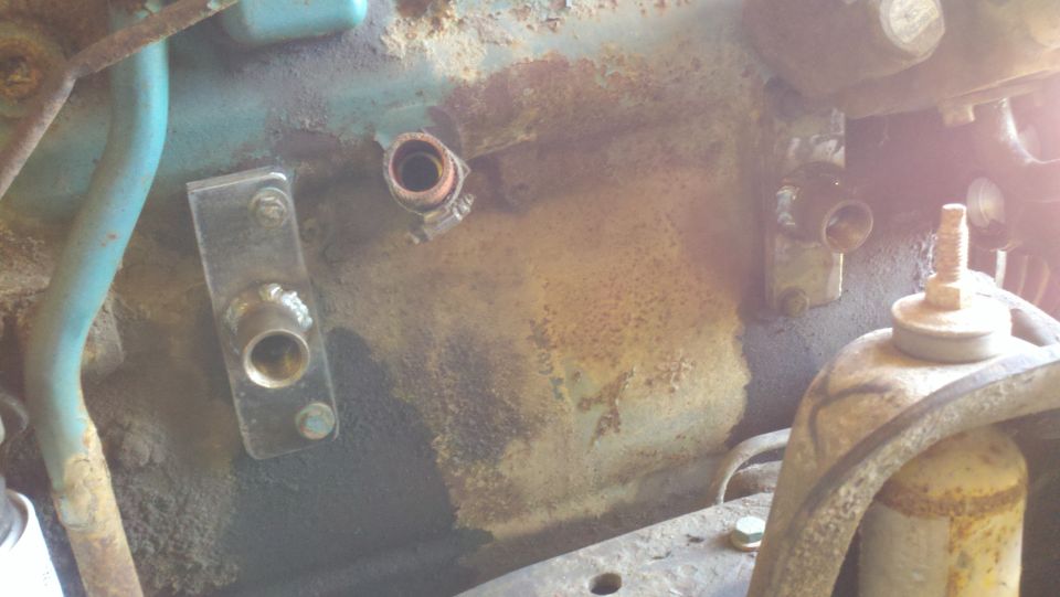 Engine bay showing metal brackets, hoses, and fittings on a rusty surface