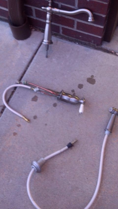 2000 Mercury Grand Marquis - Plumbing faucet and bidet sprayer parts laid out on a concrete surface.