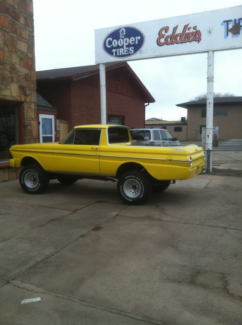 1964 Ford Ranchero - A lifted 1964 Ford Ranchero pickup truck is parked in front of a Cooper Tires and Eddie's establishment.