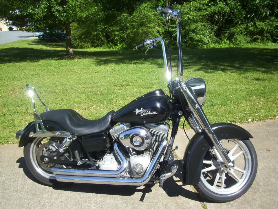 Black 2009 Harley-Davidson Super Glide motorcycle with ape handlebars parked on pavement