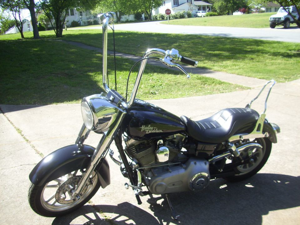 Black Harley-Davidson motorcycle with tall handlebars and a sissy bar parked on a driveway