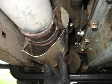 1994 Ford Bronco - Close-up of a vehicle's undercarriage, focusing on the exhaust system's heat shield.