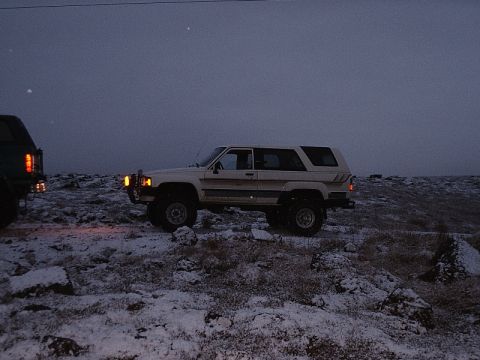1996 Ford Bronco - A white 1984 Toyota 4Runner is parked on a snowy, rocky hill next to another vehicle.