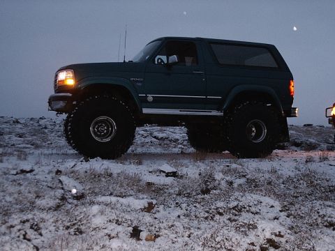1996 Ford Bronco - Dark green 1996 Ford Bronco equipped with large off-road tires sits on a snow-covered terrain.