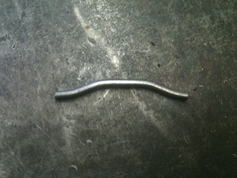 1966 Ford Bronco - A bent metal rod lies on a textured surface, possibly a workbench or floor.