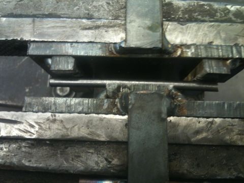 1966 Ford Bronco - Close-up of a metal rod secured in a vise, with visible welding on surrounding metal components.