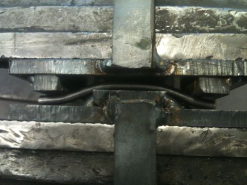 1966 Ford Bronco - A metal bar is being bent under pressure in a vise.