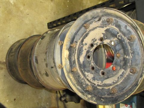 1995 Ford Bronco - Four used steel wheels are stacked on top of each other, showing signs of wear and rust.