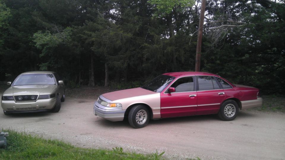 Red and tan 2000 Mercury Grand Marquis parked next to a gold sedan