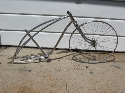 1994 Ford Bronco - A bare bicycle frame and front wheel sit on a concrete surface in front of a white wall.