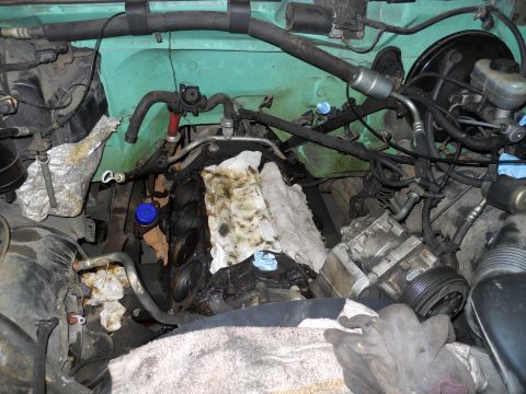 1993 Ford Bronco - The engine bay of a vehicle, with various mechanical parts and hoses visible, is shown in this photograph.