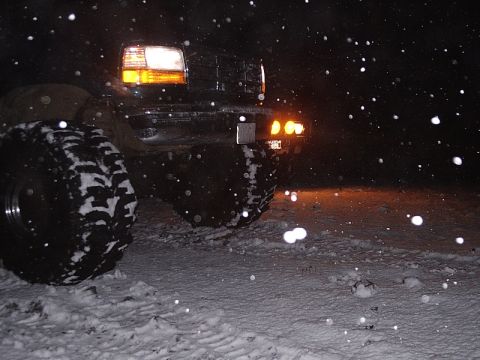 1996 Ford Bronco - 1996 Ford Bronco navigating snowy conditions at night with its lights illuminated.