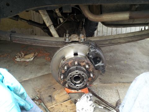 1978 Ford Bronco - Close-up view of a vehicle's rear axle and suspension components, including brake assembly and leaf springs.