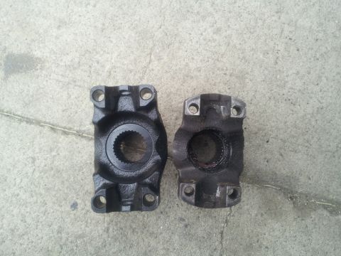1978 Ford Bronco - Comparison of a new driveshaft yoke next to a used one, both shown on a concrete surface.