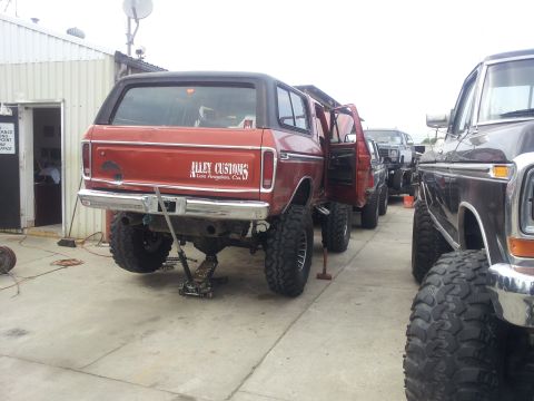 1978 Ford Bronco - Red 1978 Ford Bronco undergoing modifications, with other vehicles in the background.