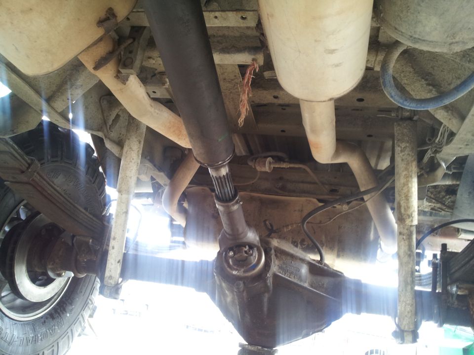 Undercarriage of a vehicle showing leaf springs, differential, driveshaft, and exhaust system