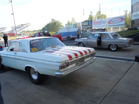 1982 Chevrolet Camaro - A white drag car with red stripes on its trunk is parked at a drag strip, with another car and an ambulance in the background.