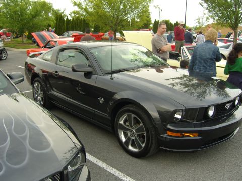 2007 Ford Mustang - A dark gray 2007 Ford Mustang is parked at an outdoor event, with other vehicles and people in the background.